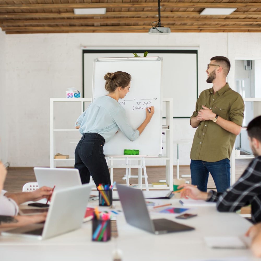young-man-eyeglasses-shirt-pretty-woman-blouse-standing-near-board-happily-presenting-new-project-colleagues-group-creative-people-working-together-modern-white-office young-man-eyeglasses-shirt-pretty-woman-blouse-standing-near-board-happily-presenting-new-project-colleagues-group-creative-people-working-together-modern-white-office
